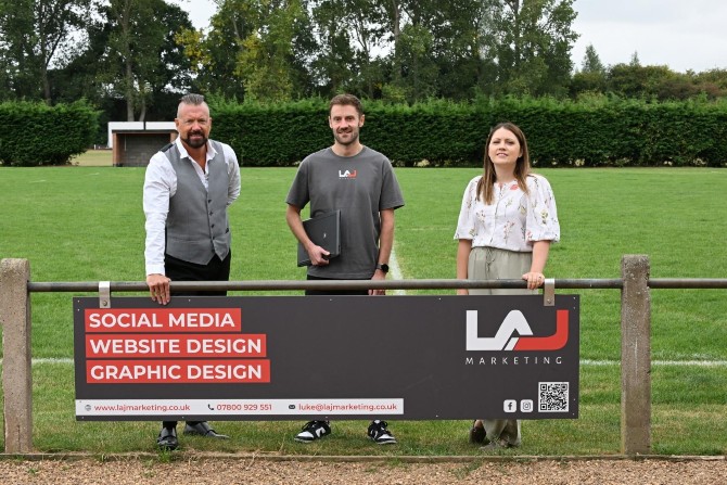 Three people stood behind a Marketing sign.
